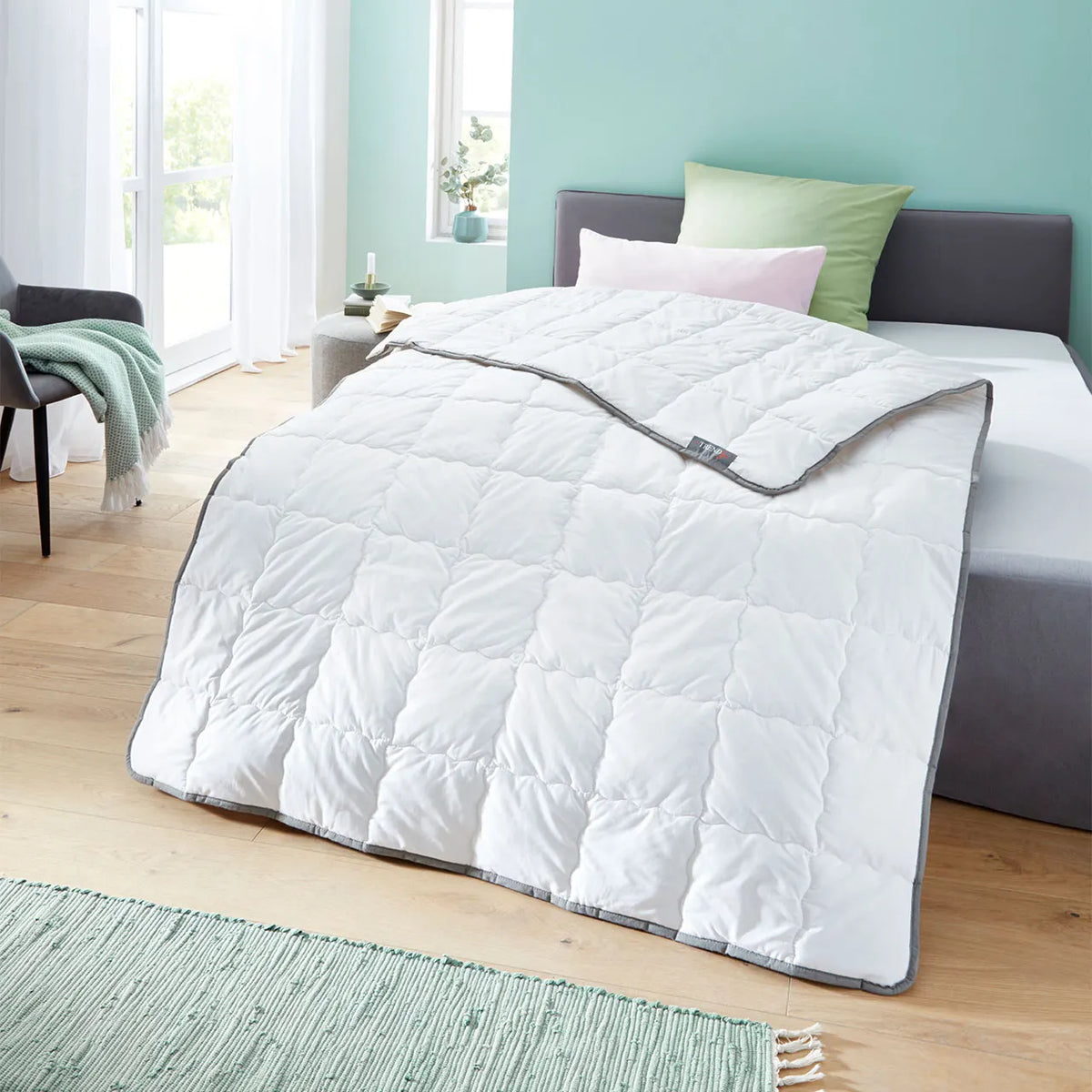 Badenia Wash Silk Bettdecke mit grauer Paspel auf einem Bett im Schlafzimmer