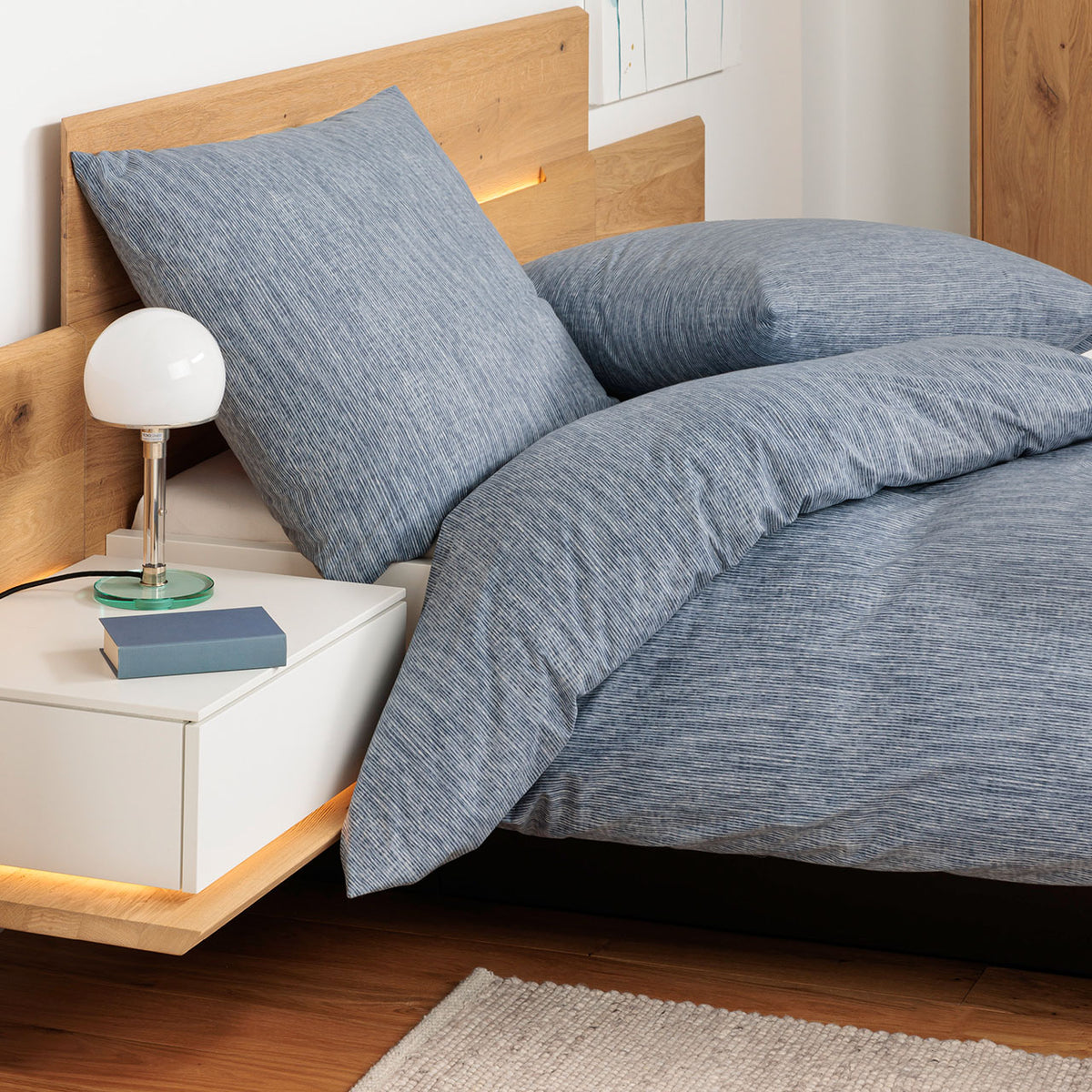 Janine Cortina Linea Bettwäsche-Set in Blau mit feiner Streifenstruktur, bezogenes Bett im Schlafzimmer