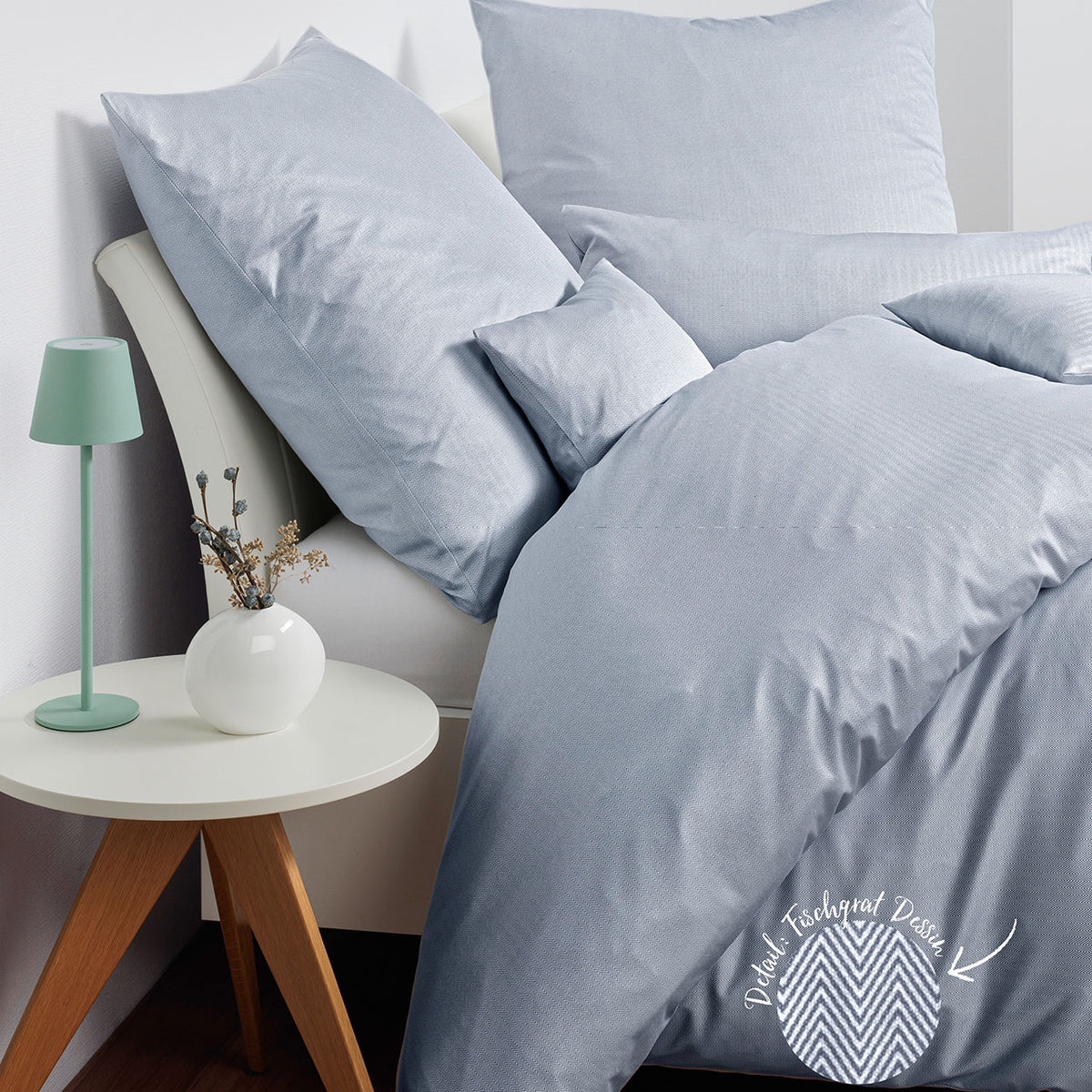 Janine Jersey Modern Classic Bettwäsche in Perlblau auf Bett, Detailkreis zeigt Fischgrat-Dessin