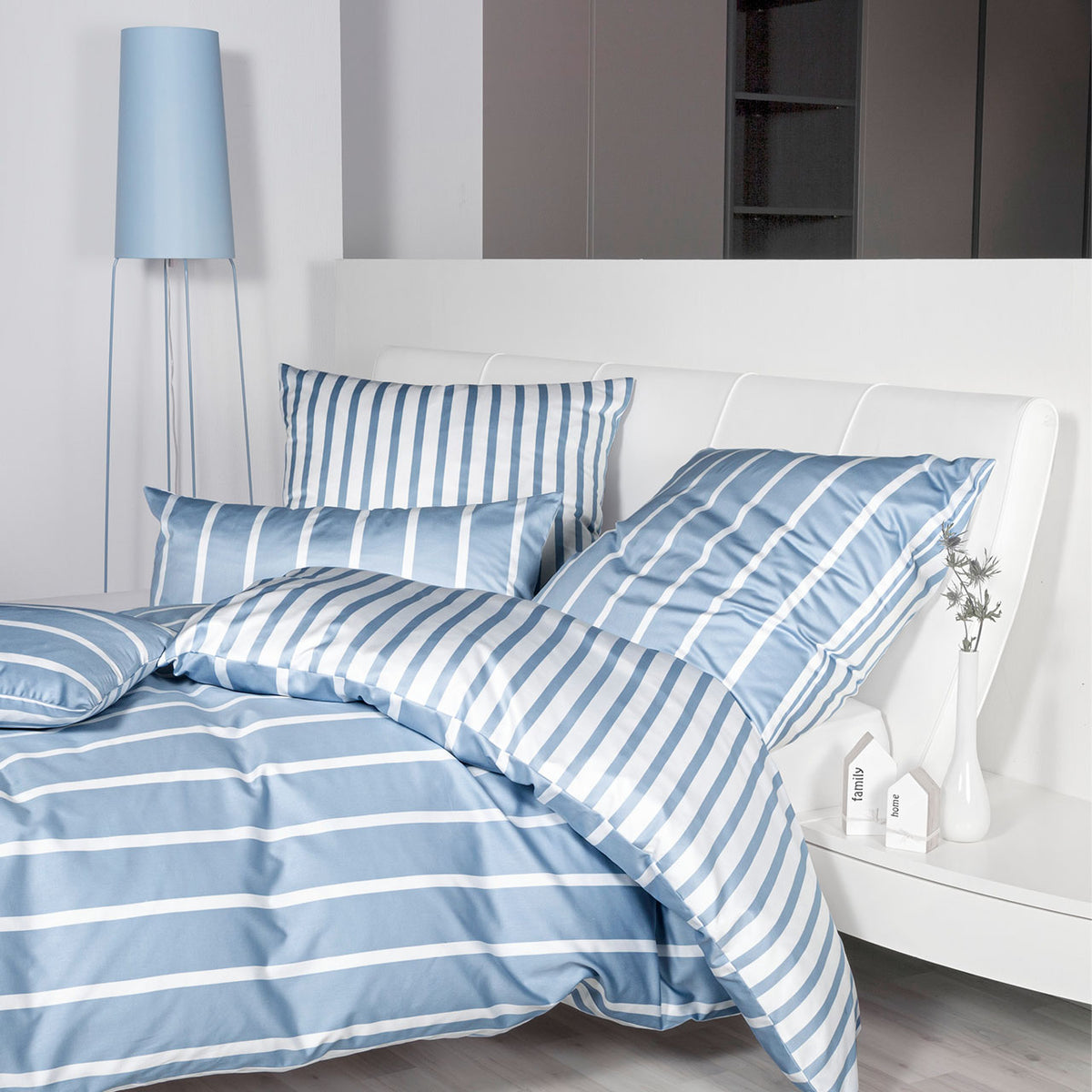 Janine Modern Classic Streifen-Bettwäsche in Perlblau-Weiß, Bett im Schlafzimmer mit blauer Stehlampe