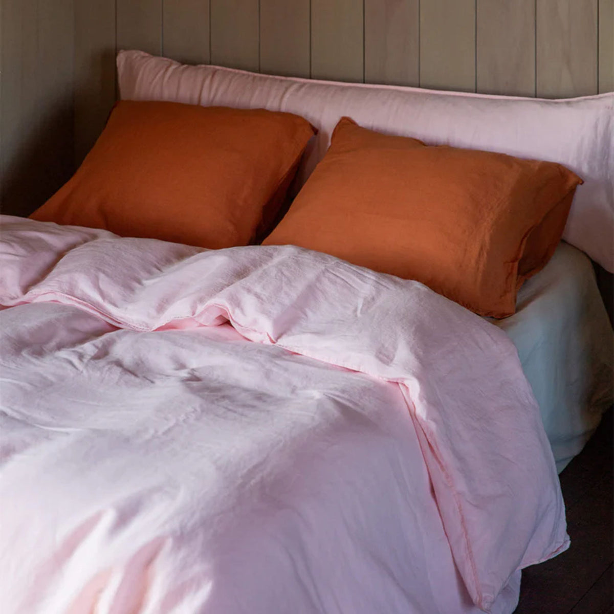 Suite702 Leinen-Mix Bettdeckenbezug in Shell Pink auf Bett mit Kissen in Terracotta, Szene im Schlafzimmer