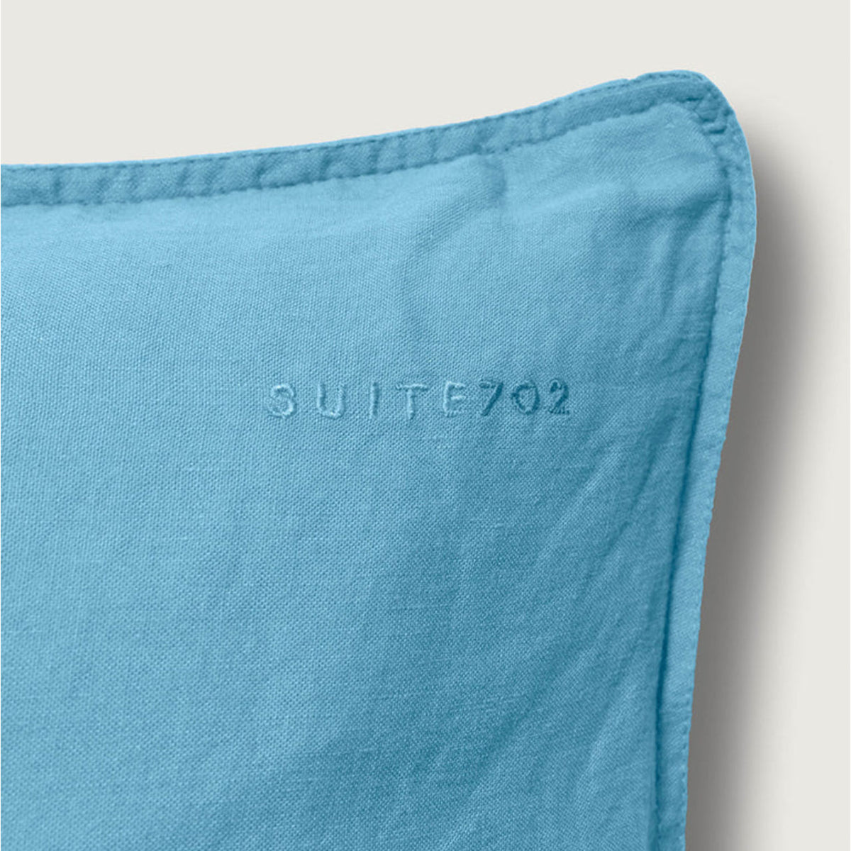 Nahaufnahme des eingestickten „Suite702“-Schriftzugs auf dem Leinen-Mix Kissenbezug in True Blue