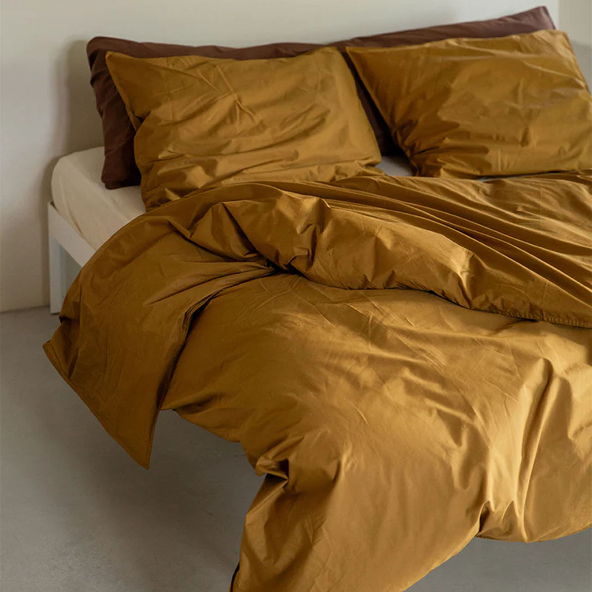 Suite702 Perkal Bettdeckenbezug aus Bio-Baumwolle in Khaki Gold auf Bett mit braunen Kissenbezügen